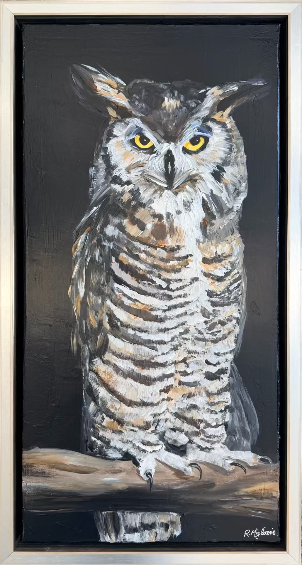A framed painting of a great horned owl perched on a branch against a dark background, with the owl rendered in white, brown, gray, and black tones with bright yellow eyes.